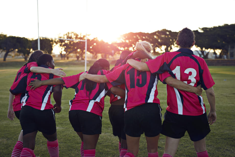 Women's rugby team walking together towards sunset.