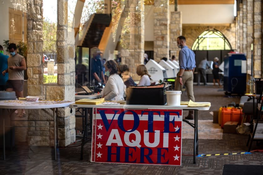 AUSTIN, TX - OCTOBER 13: Poll workers help voters inside a polling location on October 13, 2020 in Austin, Texas. The first day of voting saw voters waiting hours in line to cast their votes. Gov. Greg Abbott announced earlier this year that he would expand early voting for the election beginning on Oct. 13. Mail in voting began on Oct. 8 and has been part of a legal battle after Gov. Abbott declared each county may only have 1 mail in ballot drop off center, the ruling was later struck down in federal court but then the decision was upheld when a stay was ruled in the overturning. (Photo by Sergio Flores/Getty Images)