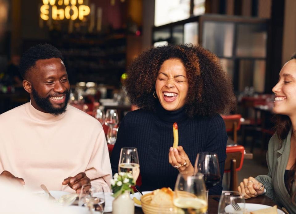 Woman eating meal and laughing in restaurant shows the fun you can have at Epicuro Culinary Center in Puerto Rico.