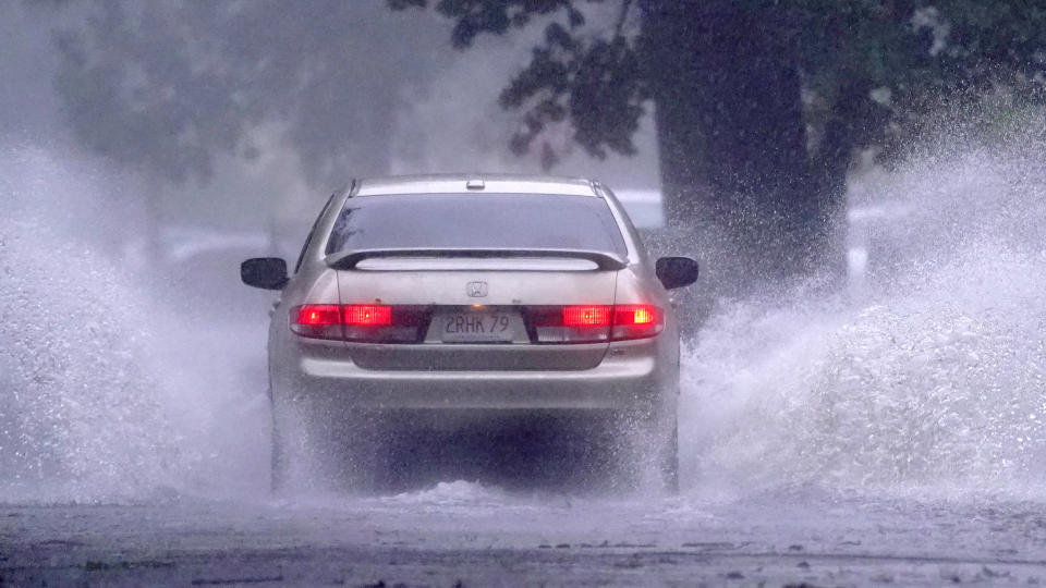 A car drives down a partially flooded street after the remnants of Hurricane Henri made landfall, Sunday, Aug. 22, 2021, in Springfield, Mass. (AP Photo/Charles Krupa)