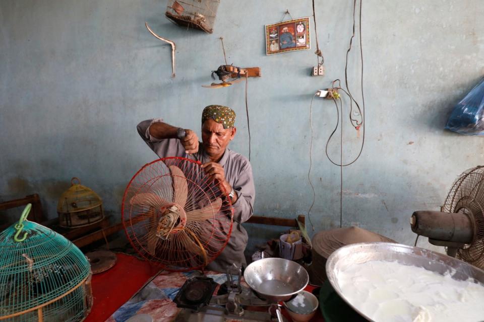 Kaloo, 60, repairs a fan with a spoon while at work in a cafe (Reuters)