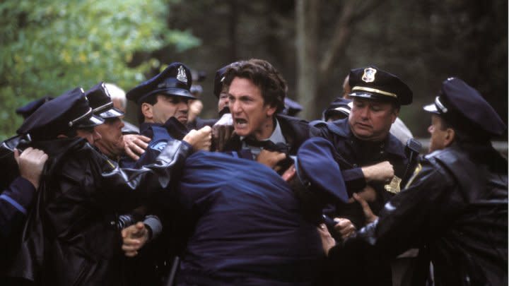 A man is held back by several policemen.