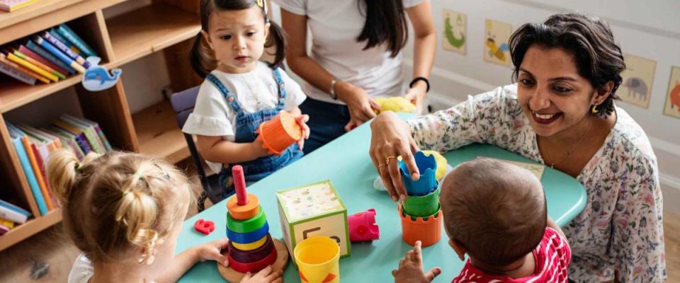 Nursery children playing with teacher in the classroom