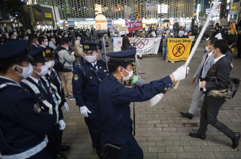FILE - In this March 25, 2021, file photo, police officers start moving to secure streets as protesters and their supporters, background, start their march against the going ahead of the Olympic and Paralympic Games (Tokyo 2020) in Tokyo. (AP Photo/Hiro Komae, File)