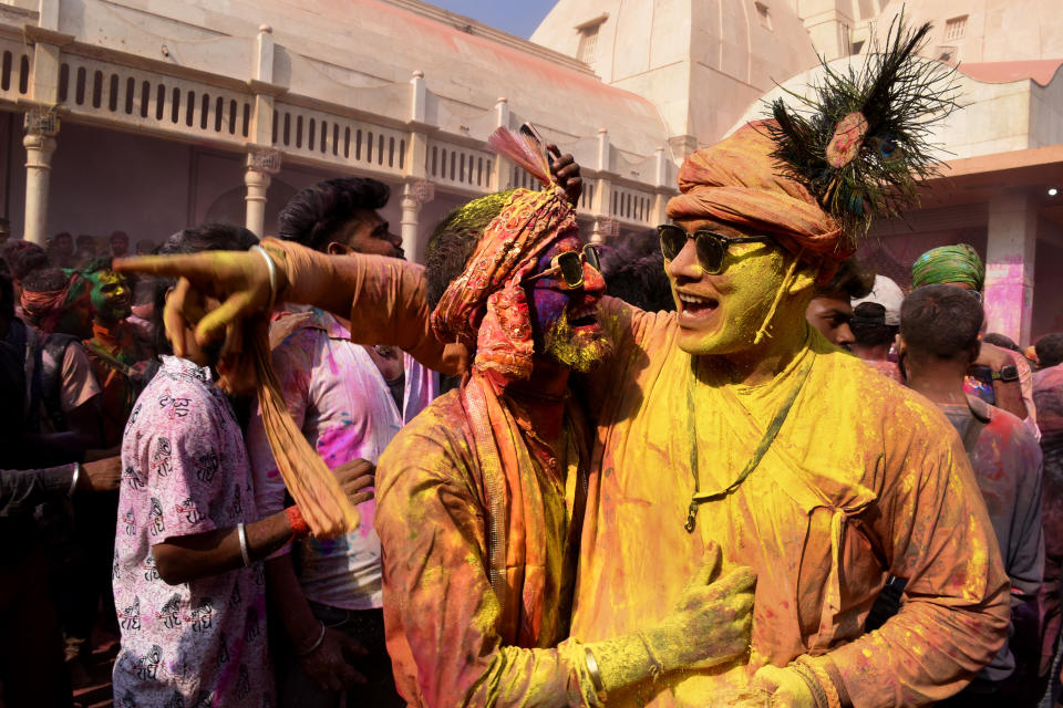 Villagers smeared with colors play Holi at Nandagram temple in Nandgoan village, 115 kilometers (70 miles) south of New Delhi, India, Wednesday, March 1, 2023. Women from Nandgaon, the birthplace of Hindu God Krishna, beat the men from Barsana, the legendary birthplace of Radha, the consort of Krishna, with wooden sticks in response to their efforts to put color on them. The same act is then replicated in Barsana between the women of that village and the men of Nandgaon as they observe the Lathmar Holi festival, a celebration of love and friendship. (AP Photo/Deepanshu Aggarwal)