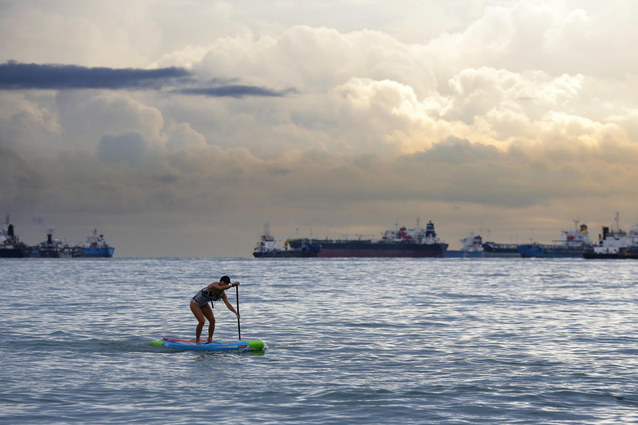 A woman on a stand up paddleboarder paddle past commercial vessels anchored at East Coast Park on 28 November 2020 in Singapore. (Photo by Suhaimi Abdullah/Getty Images)