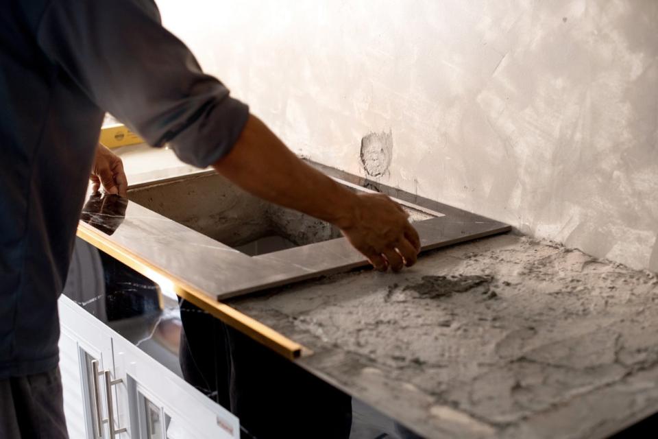 A person renovates a space with a concrete countertop.