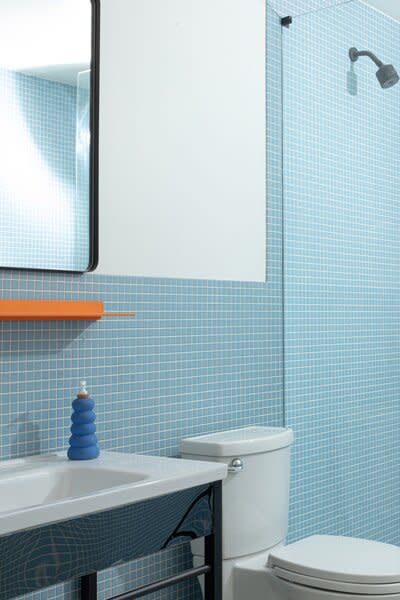 Maldonado partnered with Daltile to use matte one-inch keystone tile in a different tone for each bathroom, and suite 302 features a blue color. The orange surface is by Shelfology, and the soap bottle is Cloud 9 Clay.