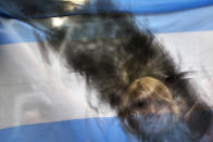 <p>A woman holds up an Argentine flag smeared with black paint, as mourners gather near the funeral home where a private wake is being held for prosecutor Alberto Nisman in Buenos Aires, Argentina, Jan. 28, 2015. On the day after he was found dead in his apartment on Jan. 18, the prosecutor was scheduled to appear before congress to detail his allegations that President Cristina Fernandez had conspired to protect some of the Iranian suspects in the 1994 bombing of a Jewish center. (Photo: Rodrigo Abd/AP) </p>