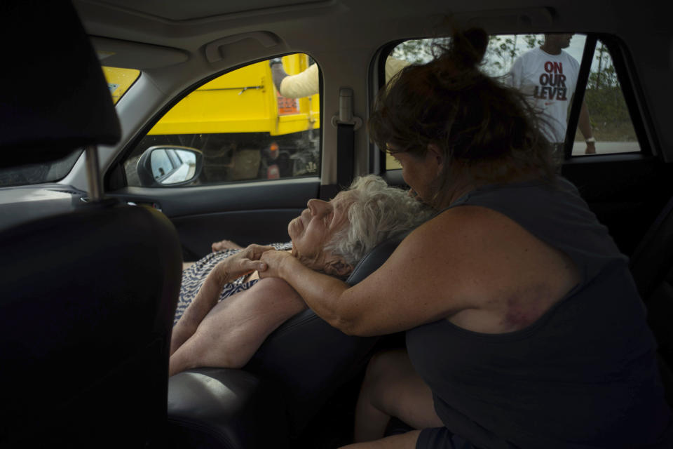 Virginia Mosvold, 84, leans back in a car seat as her daughter Sissel comforts her after they were rescued from their home on Ol' Freetown Farm that was flooded by Hurricane Dorian, before being taken to the hospital, on the outskirts of Freeport, Bahamas, Wednesday, Sept. 4, 2019. Rescue crews in the Bahamas fanned out across a blasted landscape of smashed and flooded homes trying to reach drenched and stunned victims of Hurricane Dorian and take the full measure of the disaster. (AP Photo/Ramon Espinosa)