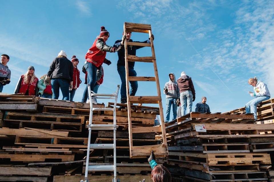 Dover High School students stack pallets and other pieces of wood Thursday as they construct a bonfire outside Crater Stadium in Dover. The bonfire is part of the annual Dover-Phila football rivalry week celebration.