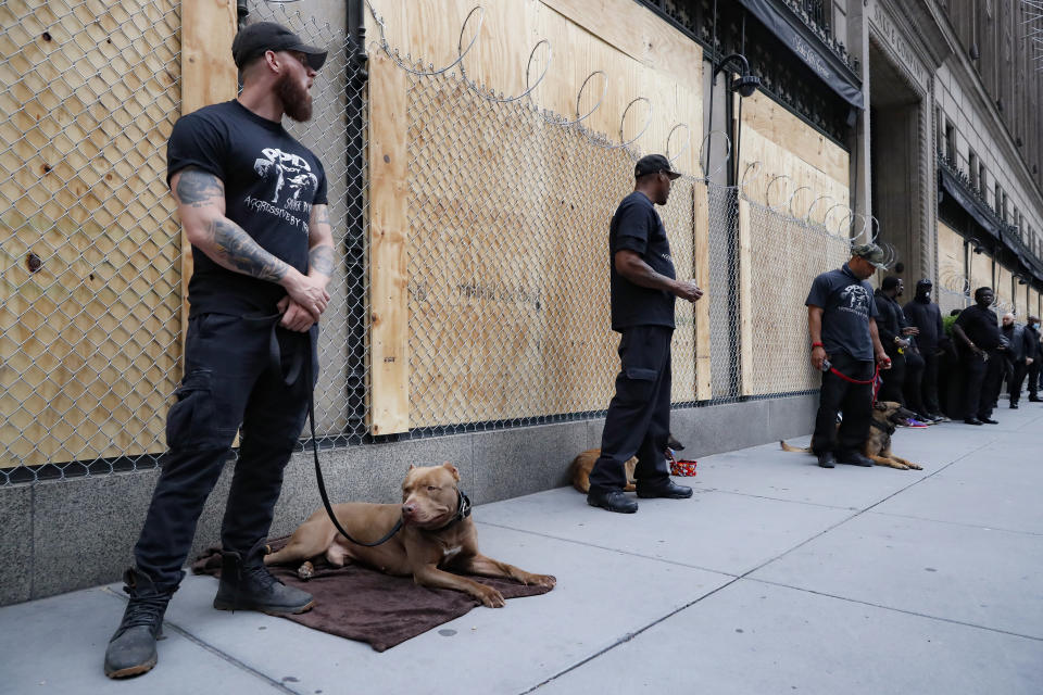 Security personnel with dogs stand guard outside Saks Fifth Avenue, Wednesday, June 3, 2020, in the Manhattan borough of New York. (AP Photo/John Minchillo)