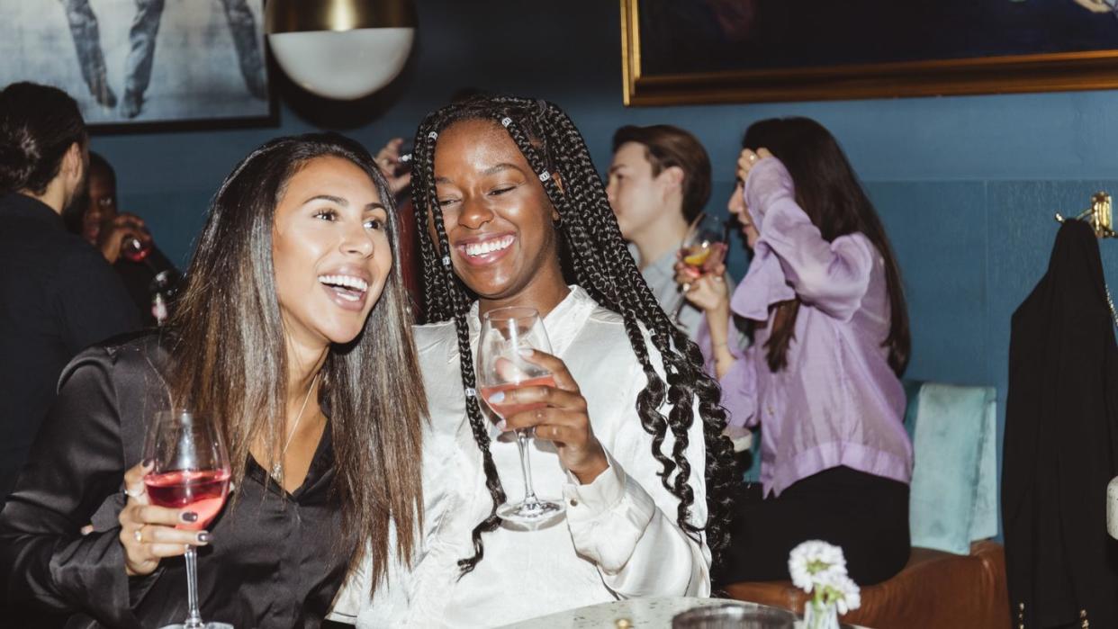 happy female and male friends having wine during party in bar