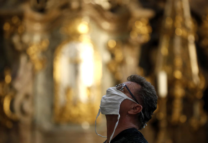 A man wearing a face mask visit the St. Nicholas church in Prague, Czech Republic, Thursday, Sept. 10, 2020. The Czech Republic is returning to mandatory mask wearing in interior spaces amid a steep rise in new coronavirus cases. Starting Thursday, people across the country need to cover their face in all public places, including stores, shopping malls, post offices and others but also in private companies where employees cannot keep a distance of 2 meters from one another. (AP Photo/Petr David Josek)