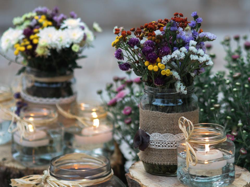 flowers in mason jars and candles on a table at a wedding