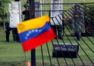 A member of the riot security forces points a gun at an opposition supporter holding a Venezuelan national flag during clashes at a rally against Venezuelan President Nicolas Maduro's government in Caracas, Venezuela June 22, 2017. REUTERS/Carlos Garcia Rawlins