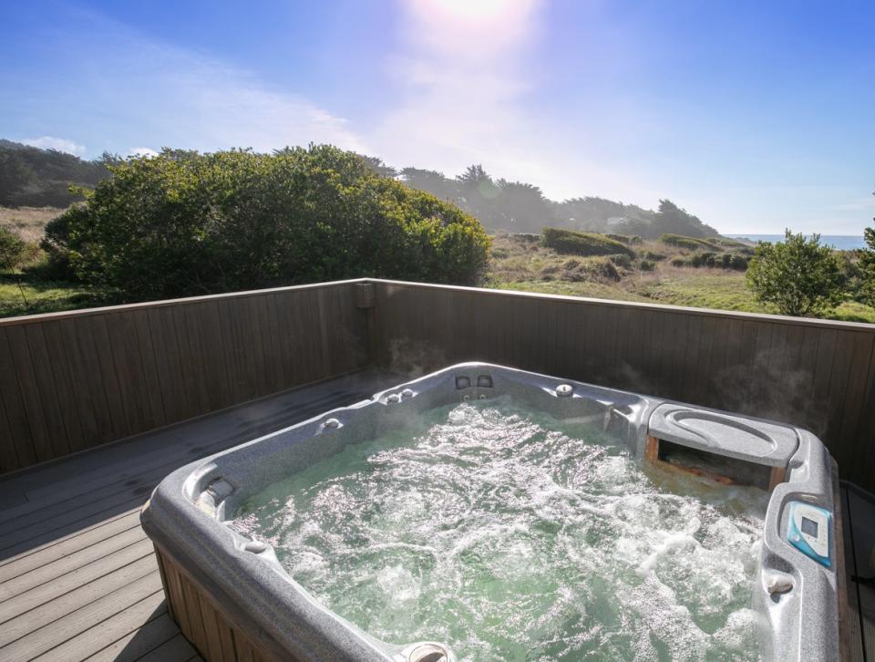 A bubbling hot tub on a home deck with a scenic landscape view in the background. 