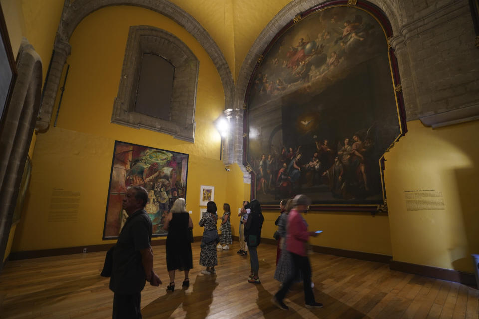 Visitors take in an exhibit in the former Jesuit college Antiguo Colegio de San Ildefonso in Mexico City, Wednesday, April 26, 2023. To honor the artwork of the artists that led the Mexican muralism movement a century ago, San Ildefonso hosts an exhibition that reflects on the significance of their monumental artworks. (AP Photo/Marco Ugarte)