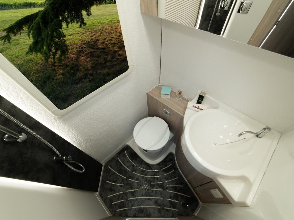 a toilet, a shower, a sink, and storage units inside the Oasi 540's bathroom
