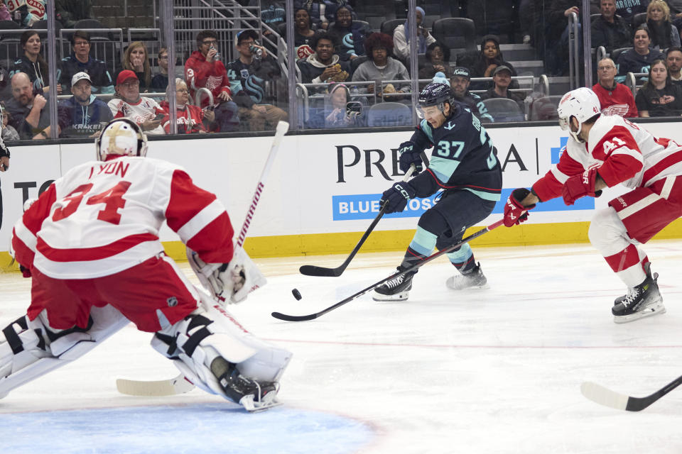 Seattle Kraken center Yanni Gourde (37) shoots on goal with only to have it blocked by Detroit Red Wings goaltender Alex Lyon (34) and defenseman Shayne Gostisbehere (41) defending during the first period of an NHL hockey game, Monday, Feb. 19, 2024, in Seattle. (AP Photo/John Froschauer)