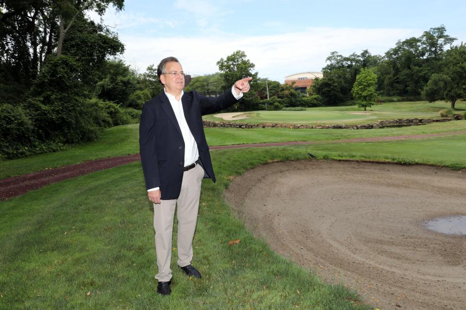 Developer Dan Pfeffer on the golf course of the Hampshire Country Club, which his company owns, July 3, 2023 in Mamaroneck. He has been fighting the village to develop condominiums there since 2014. Mamaroneck School District is considering a memorandum of understanding with the developer to accept a gift of land next to Hommocks Middle School (seen in the background) that would allow for playing fields and expansion of the building.