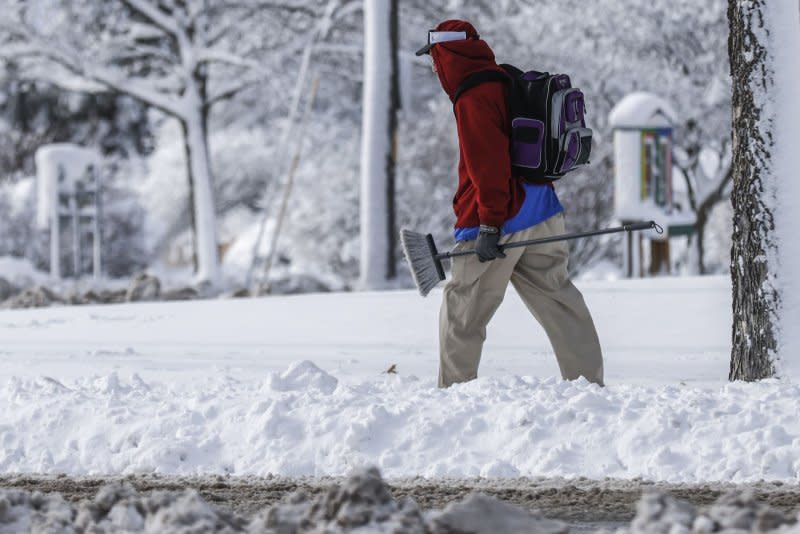 A man in Des Moines, Iowa, carries a broom as he walks along a snow-covered sidewalk earlier this week. Photo by Tannen Maury/UPI