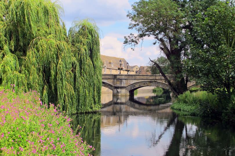 Old stone bridge across River Melland  in Stamford. Tranquil scene with reflecting water and picturesque weeping willow.  Lincolnshire, United Kingdom.