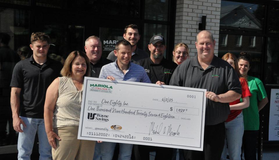 Restauranteur Mike Mariola and employees give OneEighty Executive Director Bobbie Douglas a check for roughly $1,927.