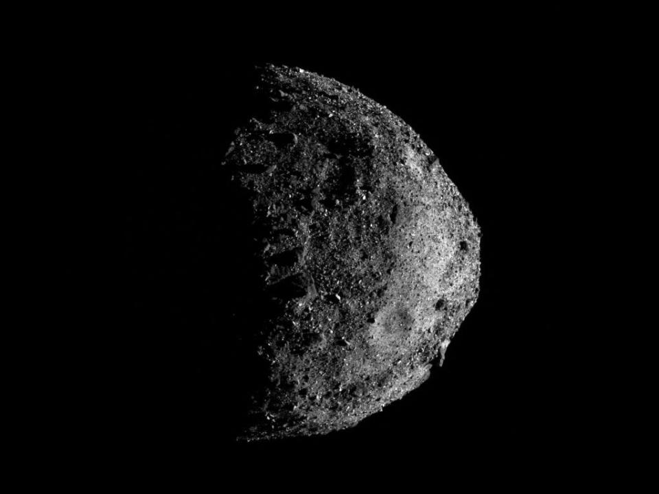 A black-and-white photo of the asteroid Bennu, which is round and full of craters