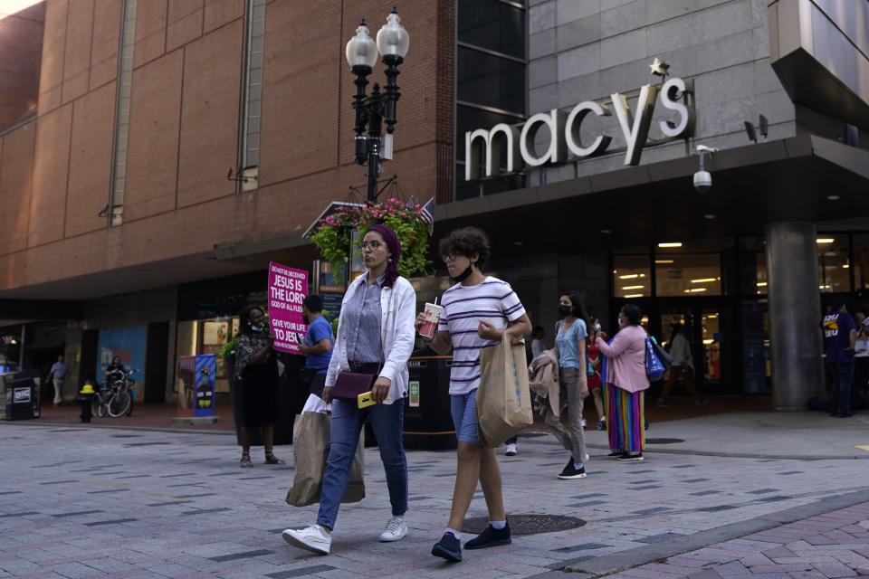 Pedestrians walk in front of a Macy's store carrying bags.