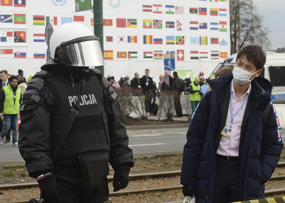 Un participante de las conferencias sobre cambio climático observa a un policía durante las protestas frente al centro de convenciones donde se lleva a cabo la cumbre de Naciones Unidas, en Katowice, Polonia, el sábado 8 de diciembre de 2018. (AP Foto/Alik Keplicz)