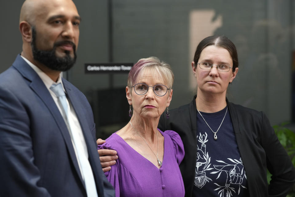 Kathleen Boleyn, center, mother of man who was fatally shot by a police officer from the Arvada, Colo., Police Department in June 2021, is hugged by her daughter, Erin Hurley, right as attorney Qusair Mohamedbhai talks about the $2.8-million settlement reached with the northwest Denver suburban city Thursday, Sept. 28, 2023, in Denver. Boleyn's son, Johnny Hurley, was shot after he had killed an active shooter who had killed an Arvada officer in the city's Olde Town area on June 21, 2021. (AP Photo/David Zalubowski)