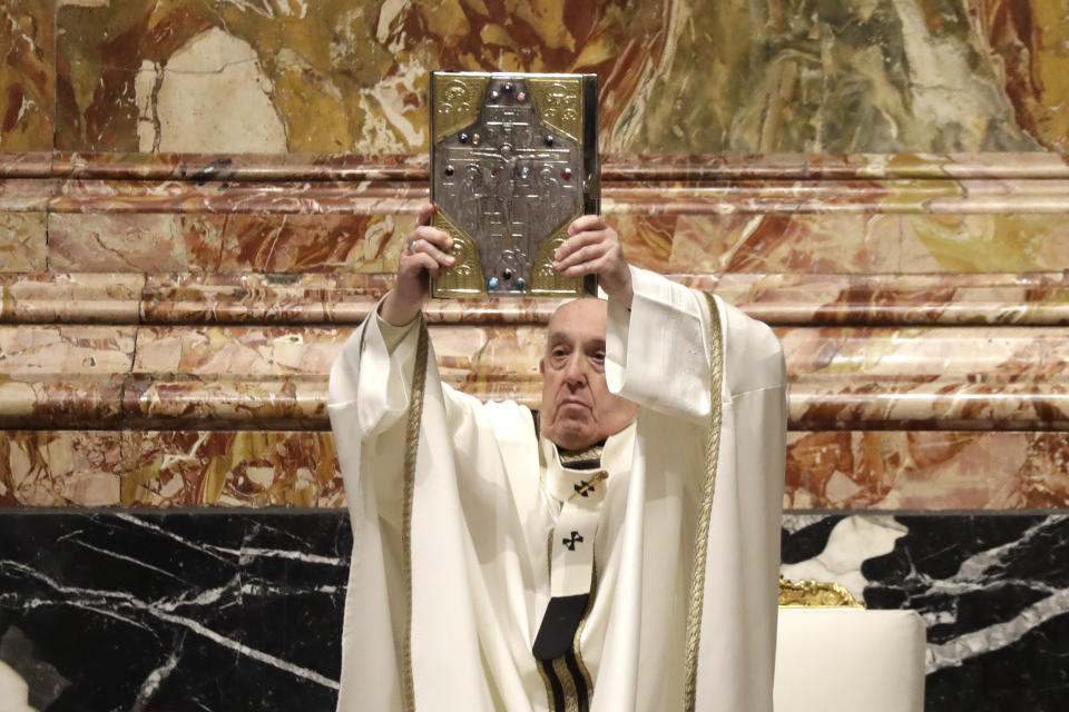 Pope Francis holds up the book of Gospels during a Chrism Mass inside St. Peter's Basilica, at the Vatican, Thursday, April 1, 2021. During the Mass the Pontiff blesses a token amount of oil that will be used to administer the sacraments for the year. (AP Photo/Andrew Medichini, pool)