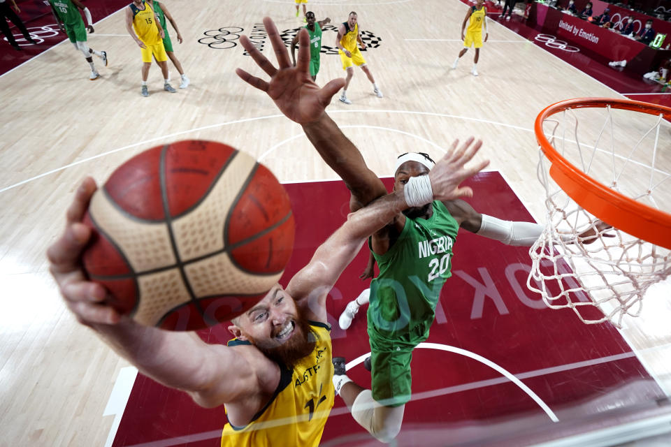 Australia's Aron Baynes, left, drives to the basket against Nigeria's Josh Okogie (20) during a men's basketball preliminary round game at the 2020 Summer Olympics, Sunday, July 25, 2021, in Saitama, Japan. (AP Photo/Eric Gay)