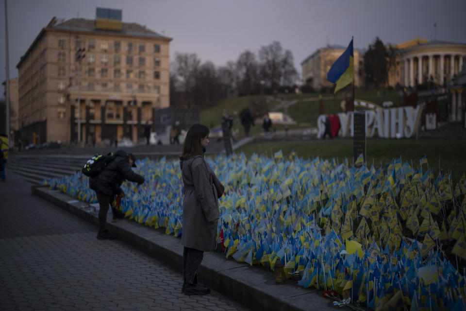 A woman stops to look at Ukrainian flags placed in memory of those killed during the war, near Maidan Square in central Kyiv, Ukraine, Friday, Jan. 20, 2023. (AP Photo/Daniel Cole)