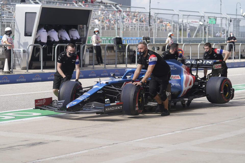 The crew for Alpine driver Fernando Alonso, of Spain, push his car back to the garage during a practice session for the F1 US Grand Prix auto race at the Circuit of the Americas, Friday, Oct. 22, 2021, in Austin, Texas. (AP Photo/Darron Cummings)