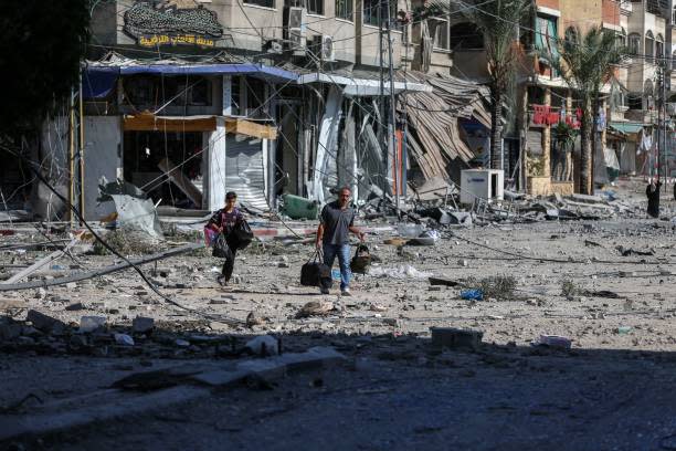 People walking amidst the destruction of houses and streets in Khan Yunis, located in the southern Gaza Strip, amid the devastation caused by Israeli airstrikes (AFP via Getty Images)