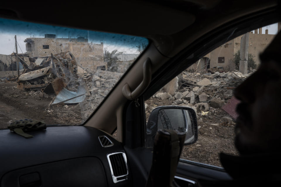 A U.S.-backed Syrian Democratic Forces (SDF) fighter rides past destroyed homes and vehicles in a village recently retaken from Islamic State militants in Susah, Syria, Saturday, Feb. 16, 2019. (AP Photo/Felipe Dana)