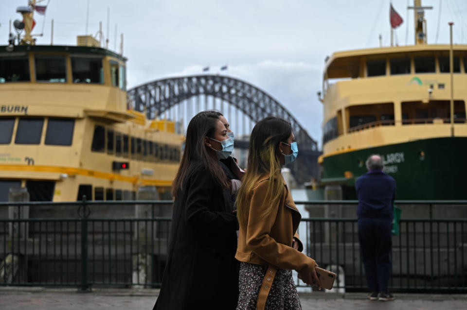 People walk past the Sydney Harbour Bridge towards the Circular Quay ferry terminal after stay-at-home orders were lifted across NSW, in Sydney,.