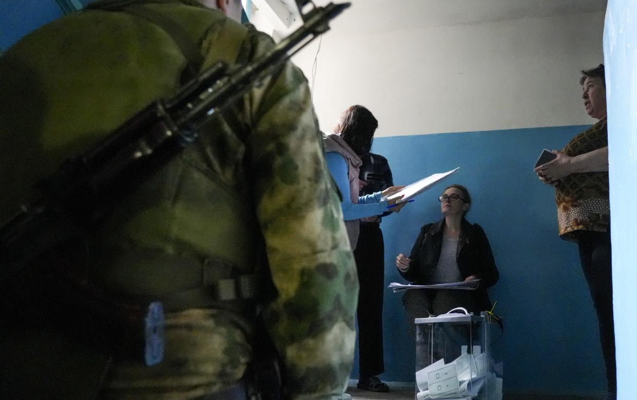 Armed occupation soldiers watch on a residents cast their votes in the sham referendums in the Donetsk region - Anadolu Agency