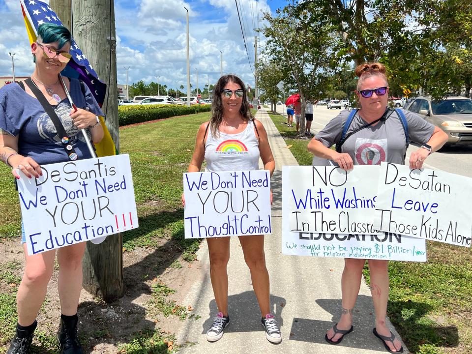 Three protesters hold signs on Beneva Road on Sunday.