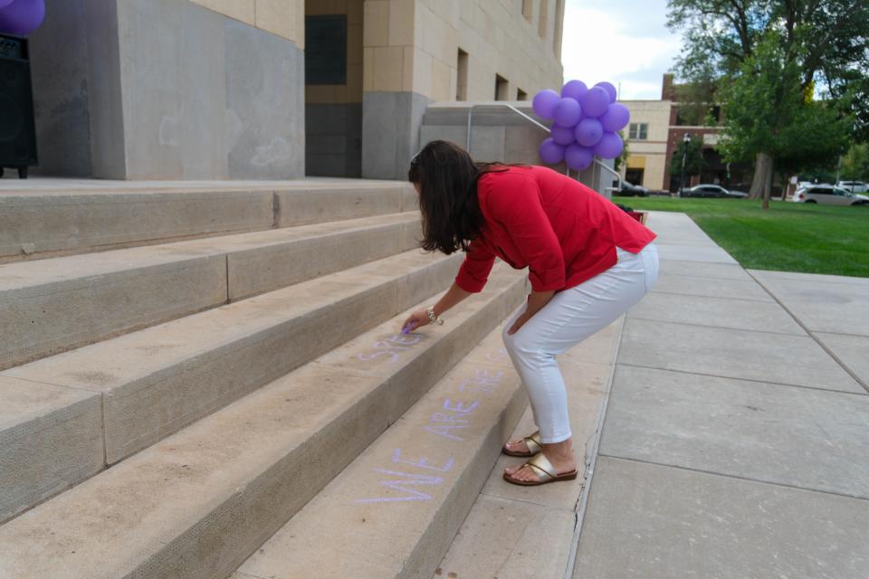 Jane Jackson, wife of Rep. Ronny Jackson, writes a message on the Potter County Courthouse steps during the Community Walk Against Domestic Violence on Monday afternoon in downtown Amarillo.