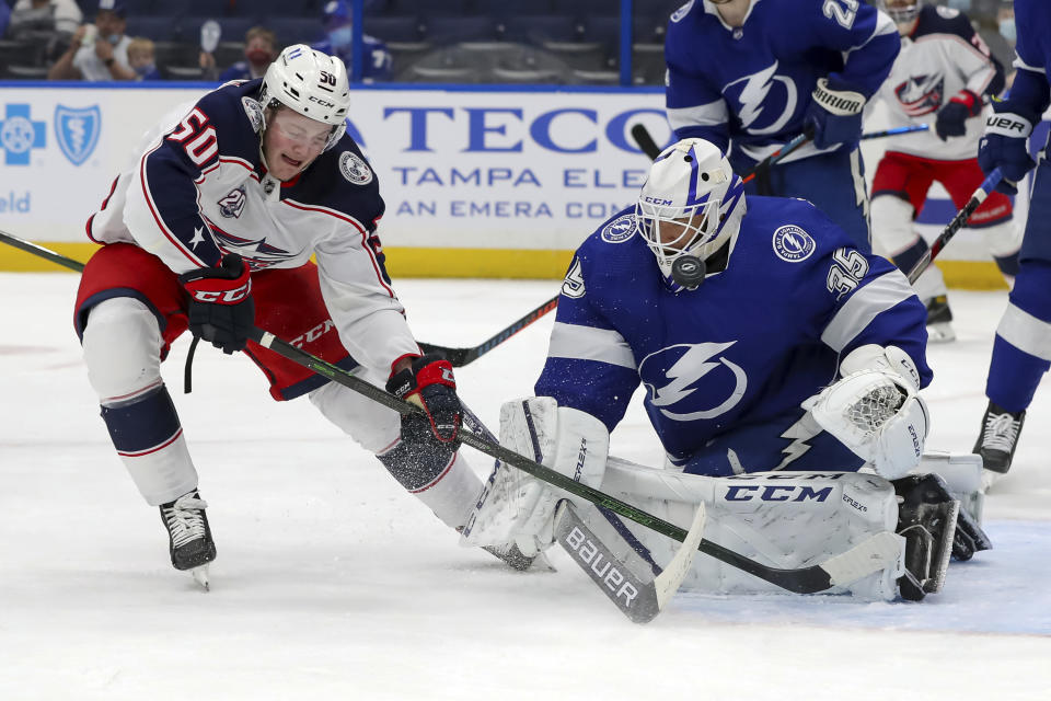 Tampa Bay Lightning goaltender Curtis McElhinney (35) makes a save against Columbus Blue Jackets' Eric Robinson during the first period of an NHL hockey game Thursday, April 22, 2021, in Tampa, Fla. (AP Photo/Mike Carlson)