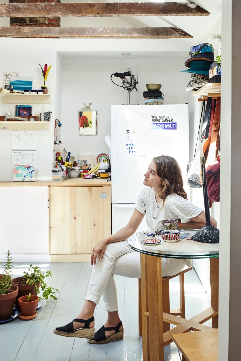 Elise in her eclectic DIY kitchen, where a little grouping of plants sits in the center of the floor.