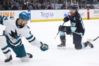 Seattle Kraken left wing Jared McCann (19) watches his shot with San Jose Sharks defenseman Jan Rutta defending during the third period of an NHL hockey game Thursday, April 11, 2024, in Seattle. (AP Photo/John Froschauer)