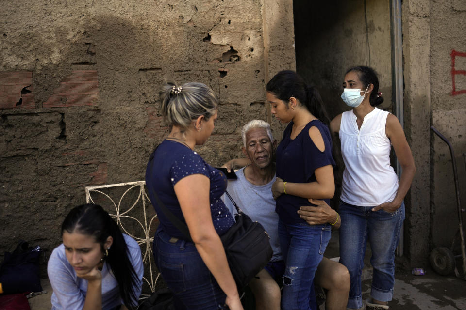 Jose Medina, center, embraces his granddaughter Enderly as neighbors stand by outside their family home that was flooded in Las Tejerias, Venezuela, Monday, Oct. 10, 2022. A fatal landslide fueled by flooding and days of torrential rain swept through this town in central Venezuela. (AP Photo/Matias Delacroix)