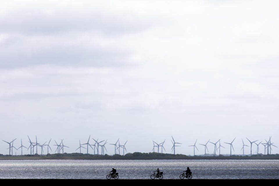 Cyclists ride their bicycles over a dyke by the sea at the island Norderney, Germany, Monday, May 25, 2020. Germany's northern states are starting to reopen the touristic hotspots after the lockdown because of the coronavirus crisis and hope that German tourists will come. (Rolf Vennenbernd/dpa via AP)