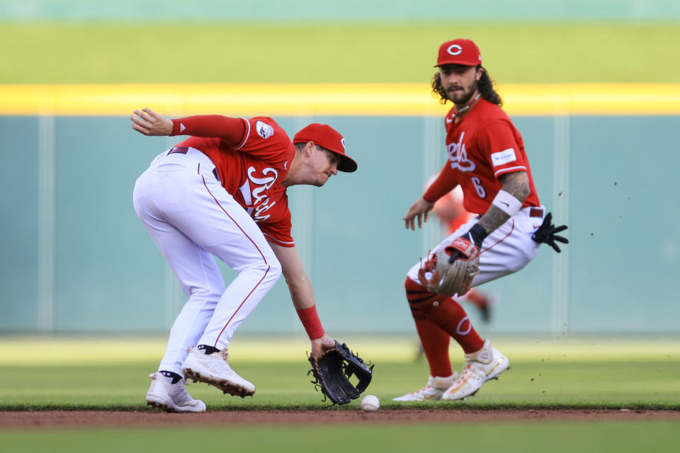 Cincinnati Reds' Kevin Newman, left, fields a ball hit by Chicago White Sox's Luis Robert Jr. for a single during the second inning of a baseball game in Cincinnati, Friday, May 5, 2023. (AP Photo/Aaron Doster)