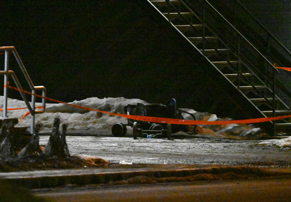A baby stroller lies on its side by police tape on the site of a fatal accident, in Amqui, Quebec, Monday, March 13, 2023. Two men died after a pickup truck plowed into pedestrians beside a road, although a senior Canadian official rapidly ruled out a terrorism attack or a national security incident. (Jacques Boissinot/The Canadian Press via AP)