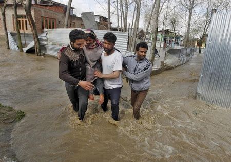 A woman is carried to a safer place from her partially submerged house after incessant rains in Srinagar March 30, 2015. REUTERS/Danish Ismail